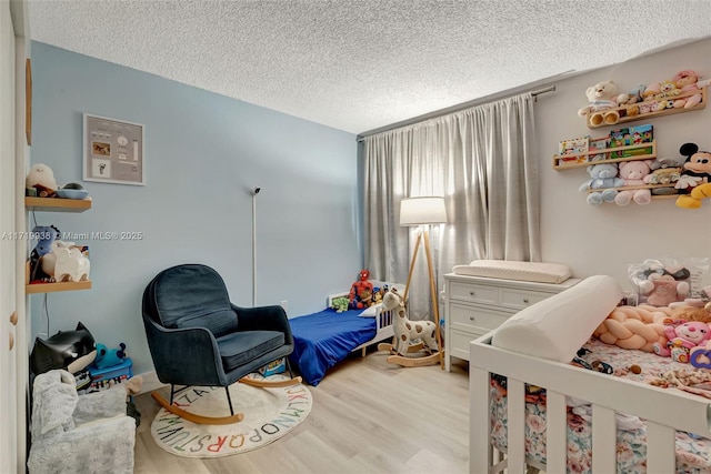 bedroom with a textured ceiling and light wood-type flooring