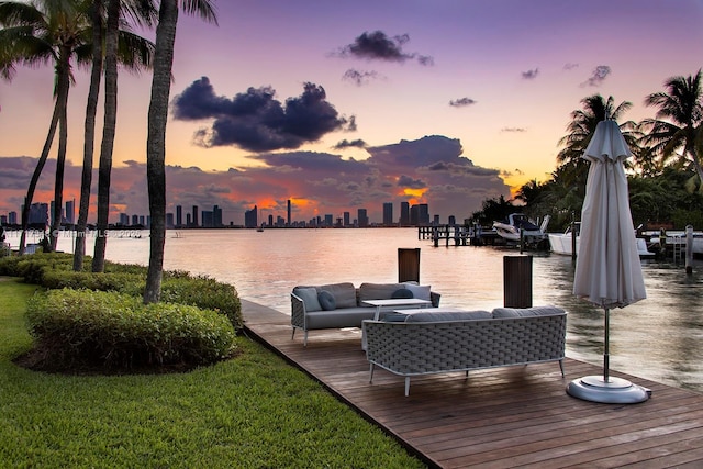 deck at dusk with an outdoor living space, a water view, and a dock