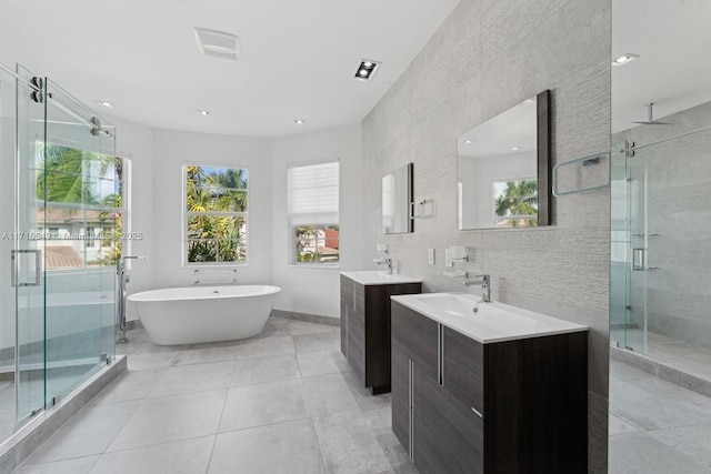 bathroom with independent shower and bath, tile walls, tile patterned floors, and vanity