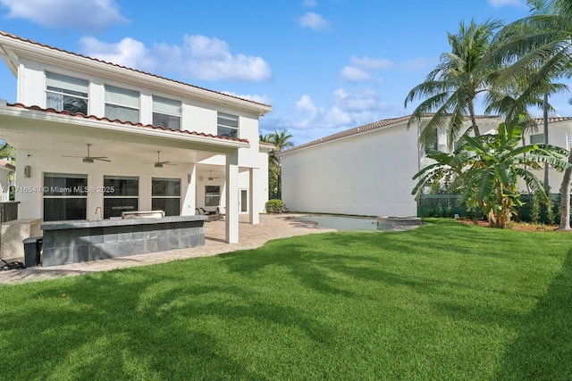 rear view of property featuring a patio, a lawn, a bar, ceiling fan, and area for grilling