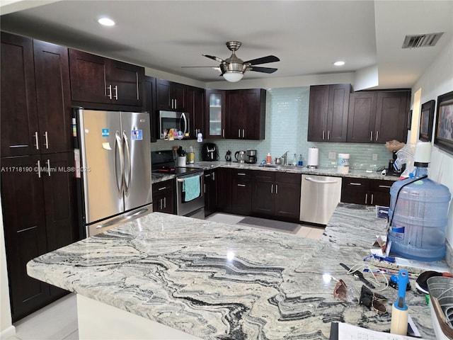 kitchen featuring backsplash, sink, light stone counters, and stainless steel appliances