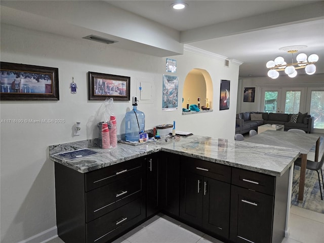 kitchen featuring kitchen peninsula, french doors, light stone countertops, ornamental molding, and light tile patterned flooring