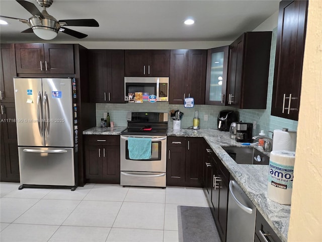 kitchen with light stone countertops, decorative backsplash, stainless steel appliances, and sink