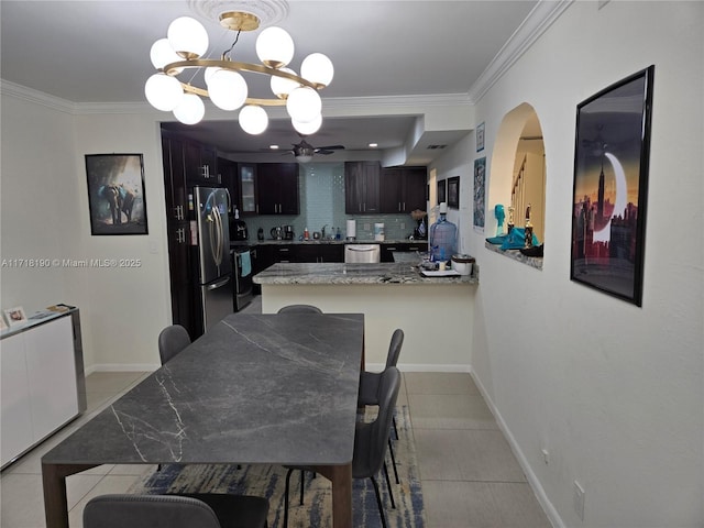 dining room with light tile patterned flooring, ceiling fan with notable chandelier, crown molding, and sink