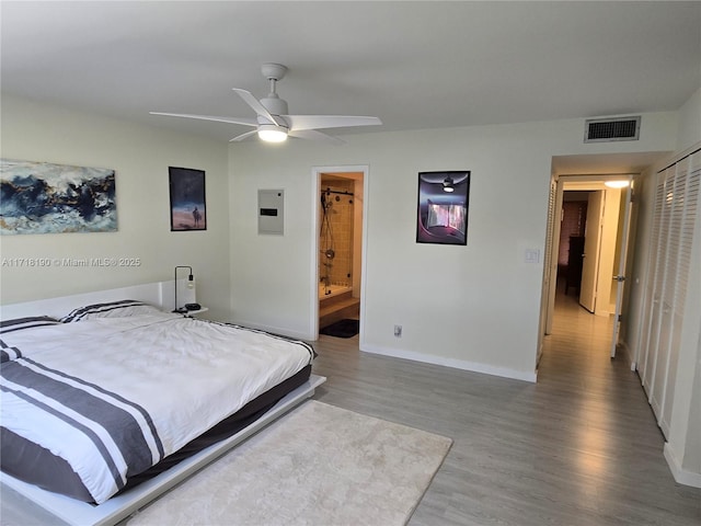 bedroom featuring connected bathroom, ceiling fan, electric panel, and hardwood / wood-style flooring