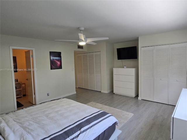 bedroom featuring ceiling fan, light hardwood / wood-style floors, and two closets