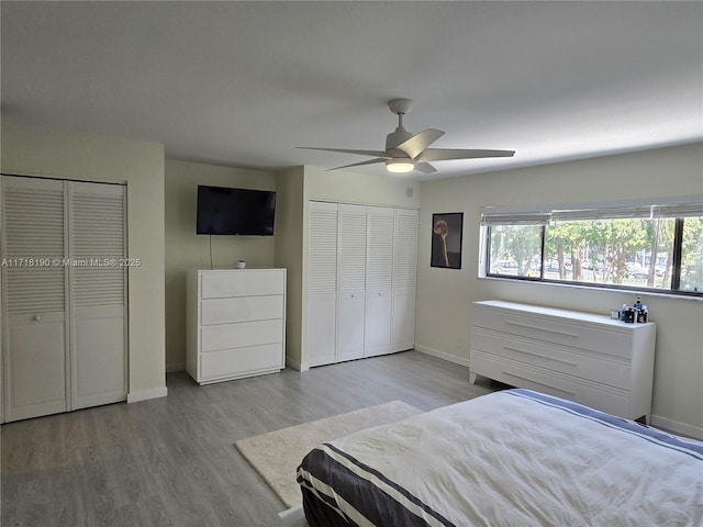 unfurnished bedroom with ceiling fan, light hardwood / wood-style flooring, and two closets