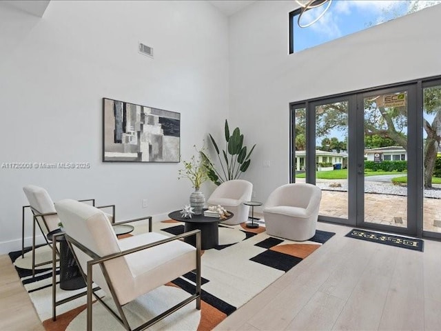 interior space featuring french doors, a towering ceiling, and hardwood / wood-style flooring