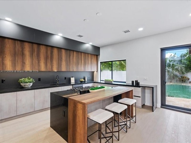 kitchen featuring butcher block countertops, a center island, sink, and a wealth of natural light