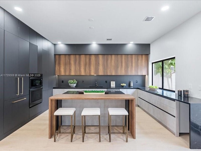 kitchen featuring sink, butcher block countertops, double oven, a breakfast bar area, and a kitchen island