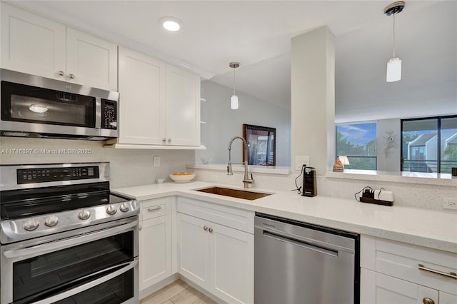 kitchen with light stone countertops, appliances with stainless steel finishes, sink, white cabinetry, and hanging light fixtures