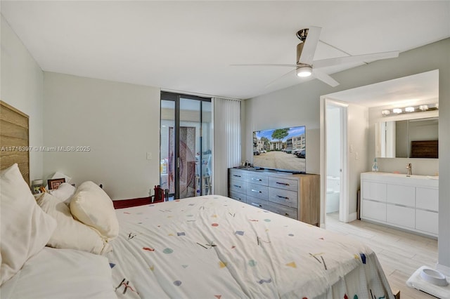 bedroom with ensuite bath, ceiling fan, sink, a wall of windows, and access to outside