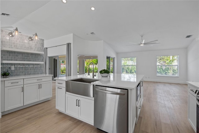 kitchen with backsplash, stainless steel appliances, sink, a center island with sink, and white cabinets