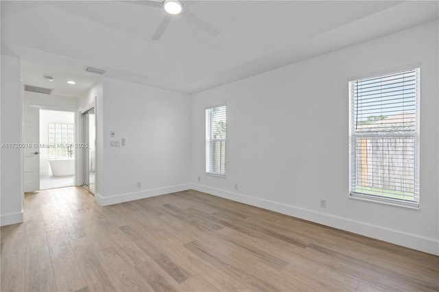 spare room featuring light hardwood / wood-style floors, ceiling fan, and a healthy amount of sunlight