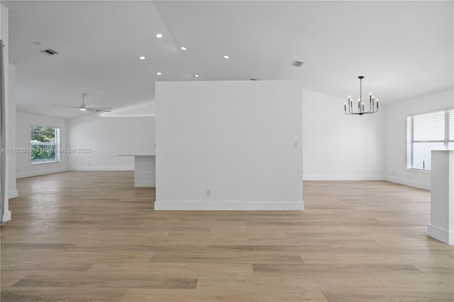 unfurnished room with ceiling fan with notable chandelier and light wood-type flooring