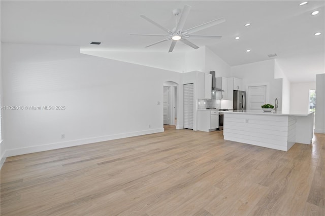 unfurnished living room featuring light hardwood / wood-style flooring, vaulted ceiling, ceiling fan, and sink