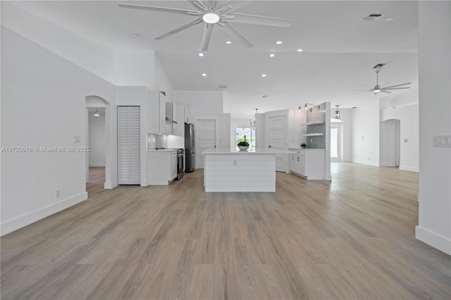 kitchen featuring ceiling fan, high vaulted ceiling, light hardwood / wood-style flooring, white cabinets, and a center island