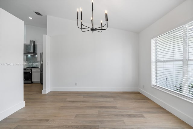 unfurnished dining area featuring light wood-type flooring and a notable chandelier