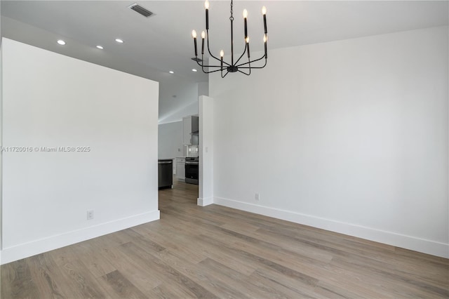 spare room featuring a notable chandelier and light hardwood / wood-style flooring