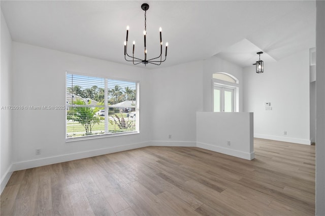 spare room with light hardwood / wood-style flooring and a chandelier