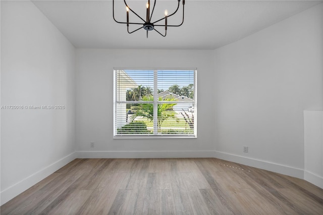 spare room with a chandelier and light hardwood / wood-style flooring