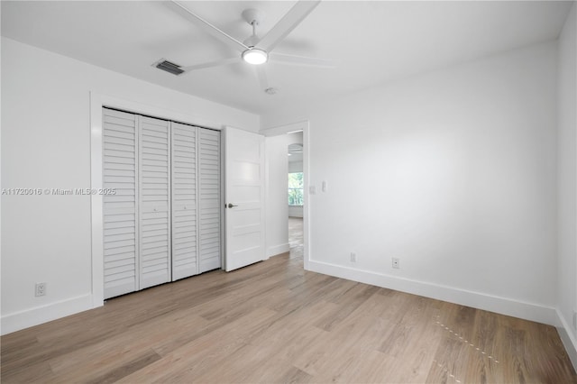 unfurnished bedroom with ceiling fan, light wood-type flooring, and a closet