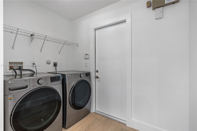 washroom with washer and clothes dryer and light wood-type flooring