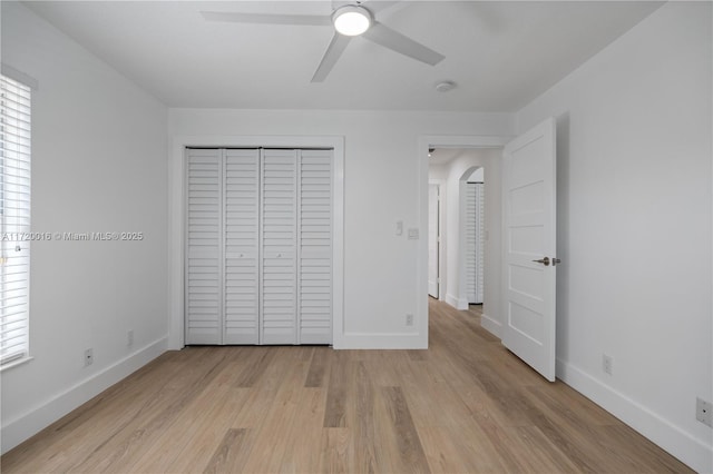 unfurnished bedroom featuring ceiling fan, a closet, and light wood-type flooring