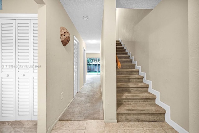 staircase with tile patterned flooring and a textured ceiling