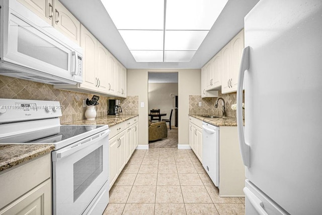 kitchen with white cabinetry, sink, light stone countertops, and white appliances