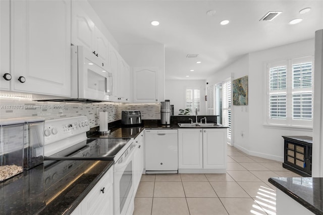 kitchen featuring white cabinetry, sink, dark stone counters, and white appliances