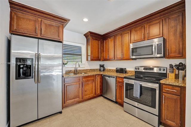 kitchen featuring light stone counters, appliances with stainless steel finishes, sink, and light tile patterned floors