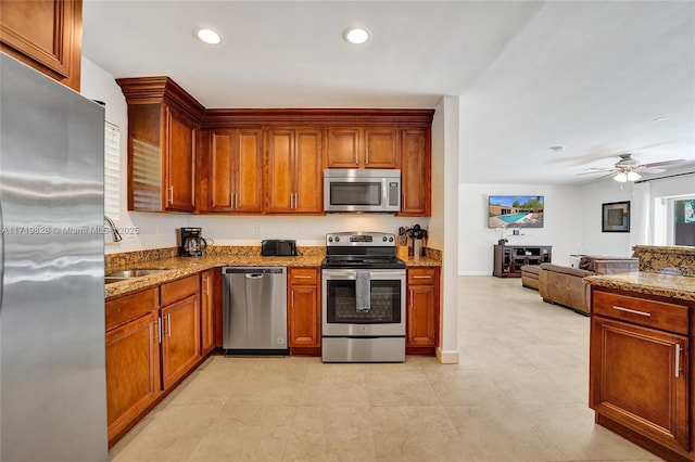 kitchen with ceiling fan, stainless steel appliances, sink, and stone counters