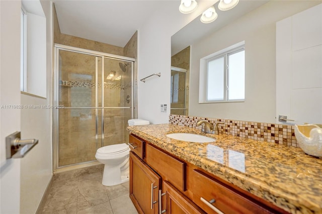 bathroom with tasteful backsplash, vanity, a shower with door, and toilet