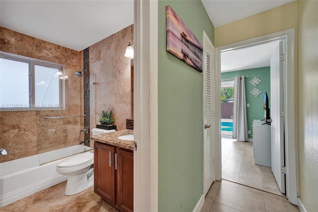 full bathroom featuring toilet, tiled shower / bath, tile walls, vanity, and tile patterned flooring