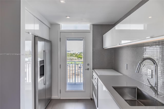 kitchen with sink, white cabinetry, high quality fridge, and plenty of natural light