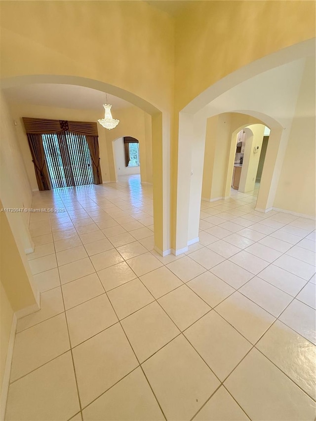 empty room featuring light tile patterned floors and an inviting chandelier