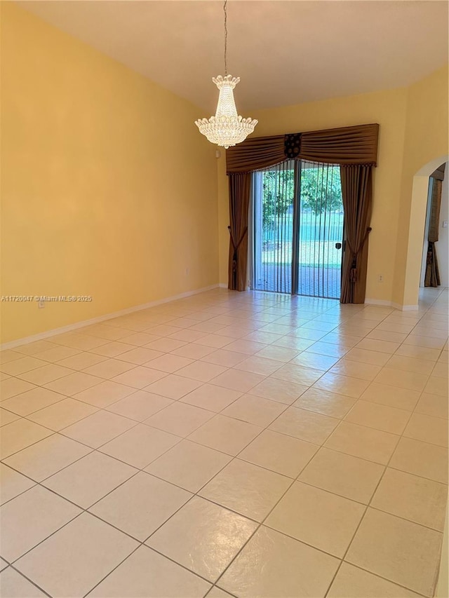 spare room featuring a notable chandelier and light tile patterned floors