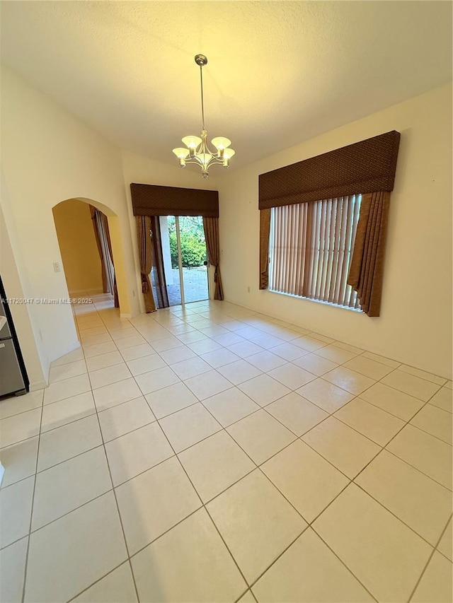 unfurnished room featuring light tile patterned floors, a chandelier, and vaulted ceiling