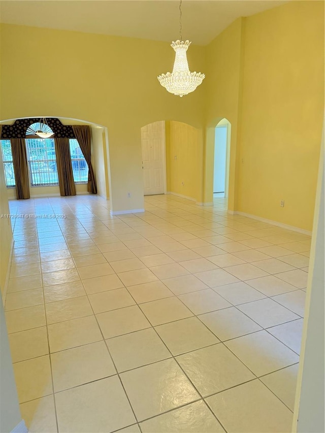 spare room with light tile patterned floors and an inviting chandelier