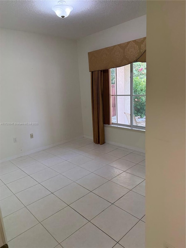 unfurnished room featuring light tile patterned flooring and a textured ceiling