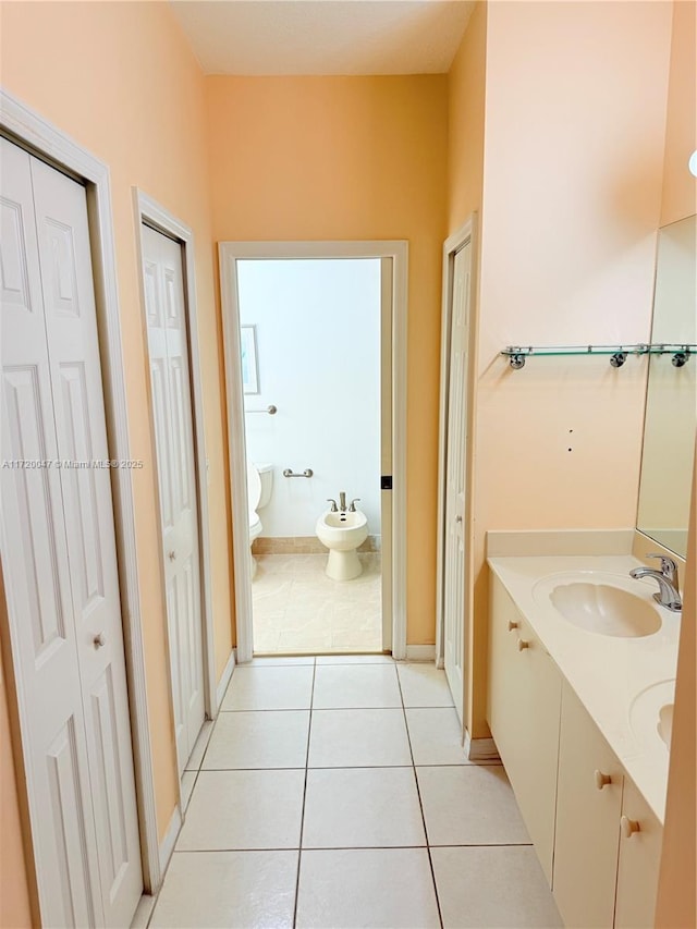 bathroom featuring tile patterned flooring, vanity, toilet, and a bidet