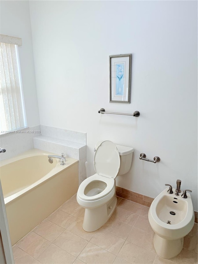 bathroom featuring tile patterned floors, a bathtub, a bidet, and toilet