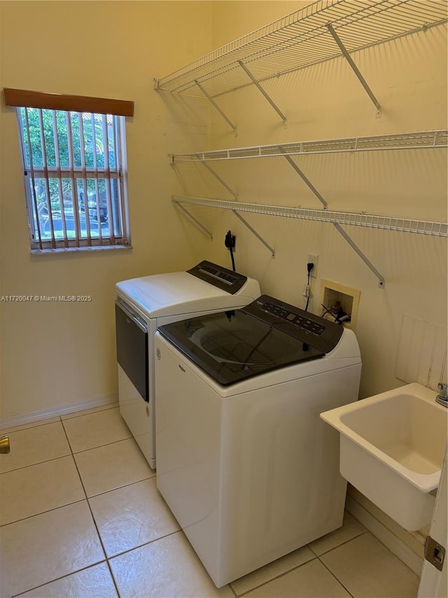 laundry room featuring light tile patterned floors, washer and clothes dryer, and sink