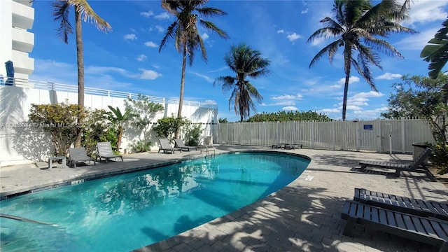 community pool with a patio and fence