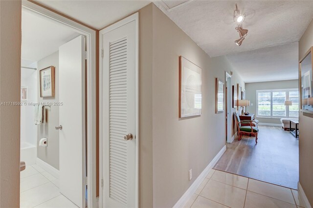 hall featuring light tile patterned flooring and a textured ceiling