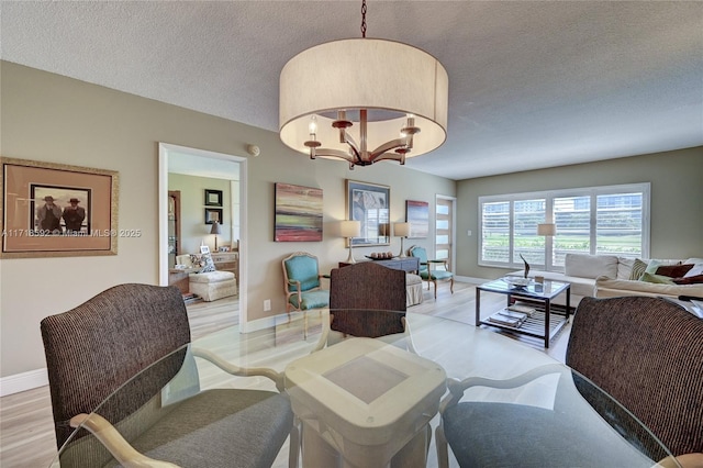 dining space featuring a chandelier, a textured ceiling, and light wood-type flooring