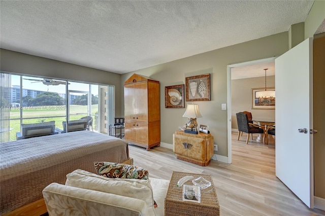 bedroom featuring access to exterior, light hardwood / wood-style floors, and a textured ceiling