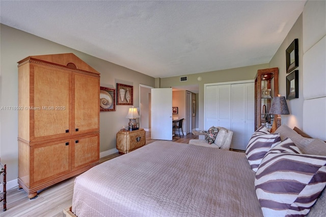 bedroom with light wood-type flooring and a textured ceiling