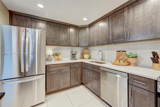 kitchen featuring backsplash, dark brown cabinetry, sink, and appliances with stainless steel finishes